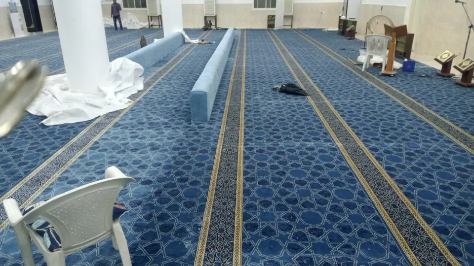 قاعة صلاة واسعة بسجاد أزرق وخطوط صلاة متوازية